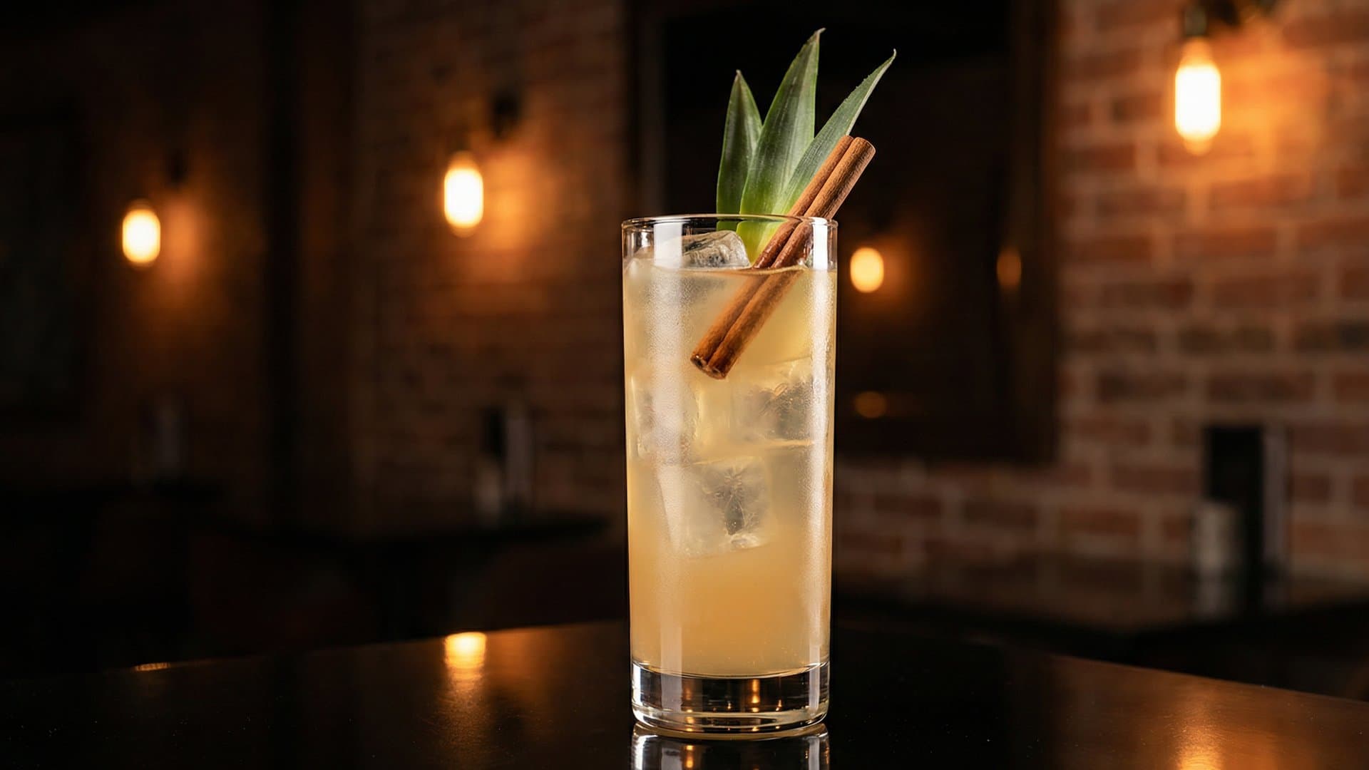 Tepache Ahumado cocktail in a Collins garnished with Pineapple frond and cinnamon stick