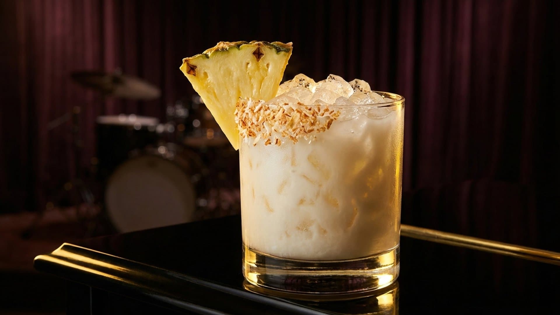 Island Fortune cocktail in a double rocks glass garnished with pineapple wedge and toasted coconut flakes