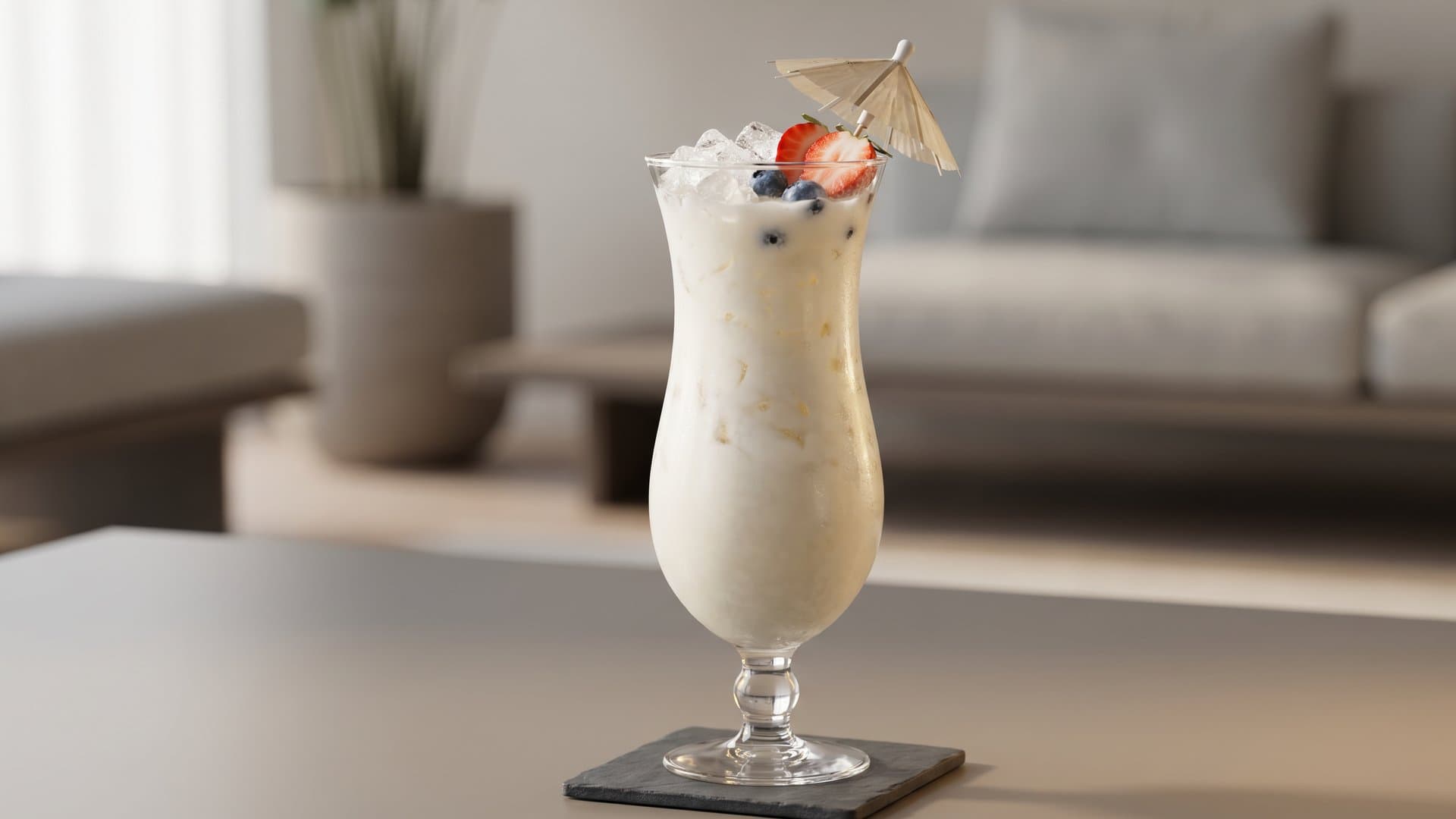 Stars & Stripes Colada cocktail in a hurricane glass garnished with strawberry slice, fresh blueberries, and cocktail umbrella or flag pick