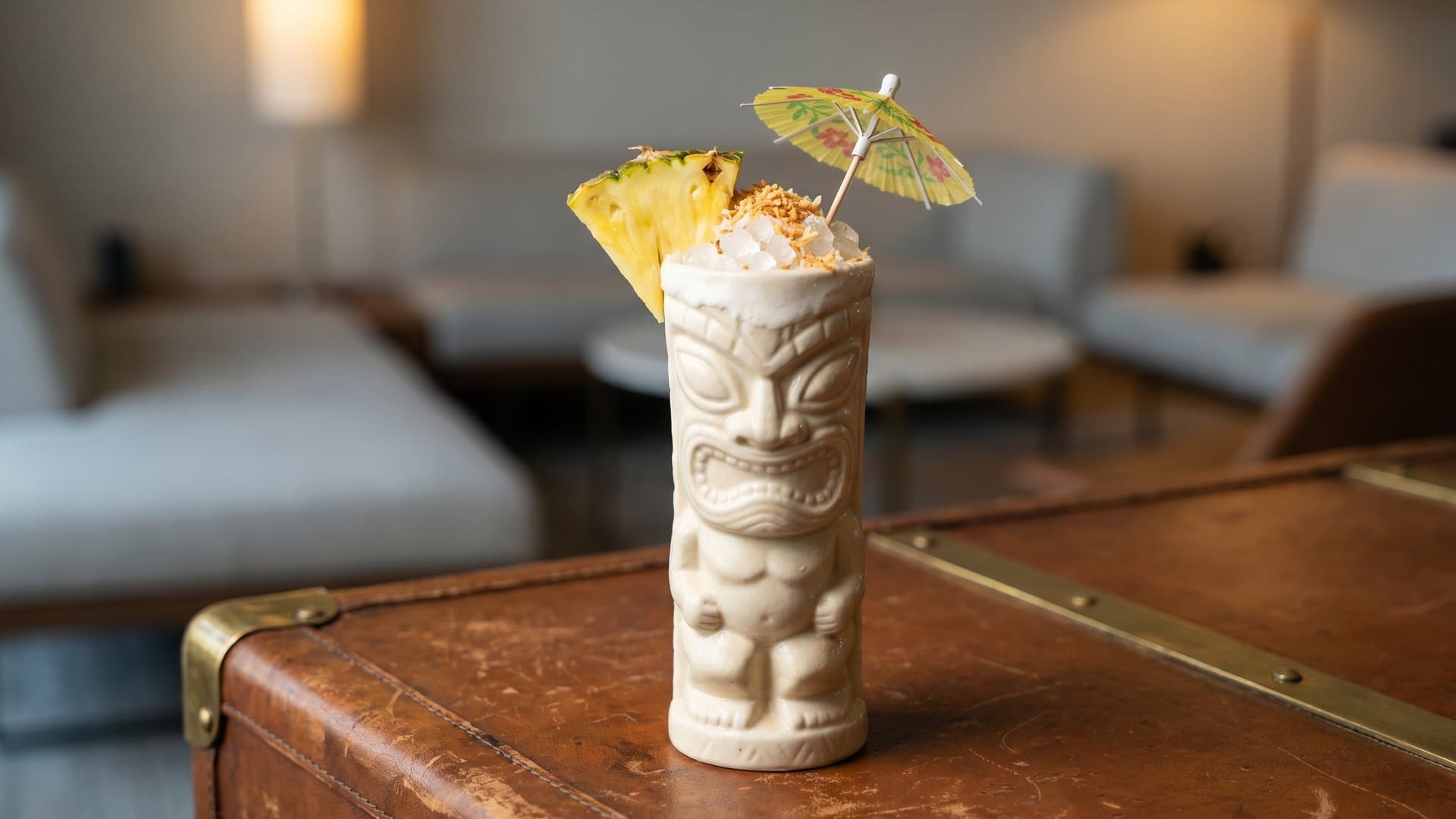 Island Mirage cocktail in a tiki mug or hurricane glass garnished with Fresh pineapple wedge, toasted coconut flakes, cocktail umbrella