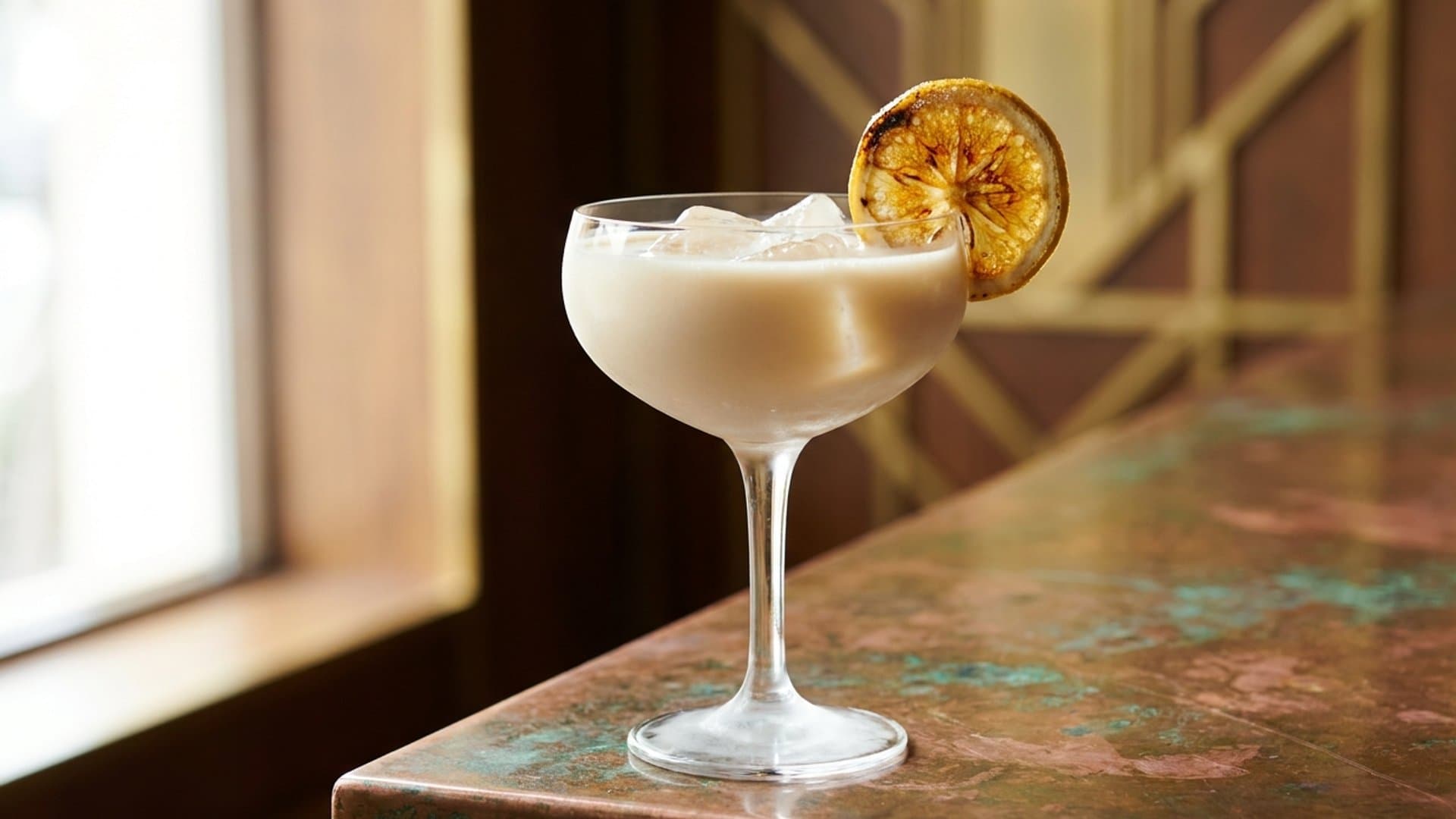Torched Sugar cocktail in a coupe garnished with Torched demerara sugar crust on half a lemon wheel