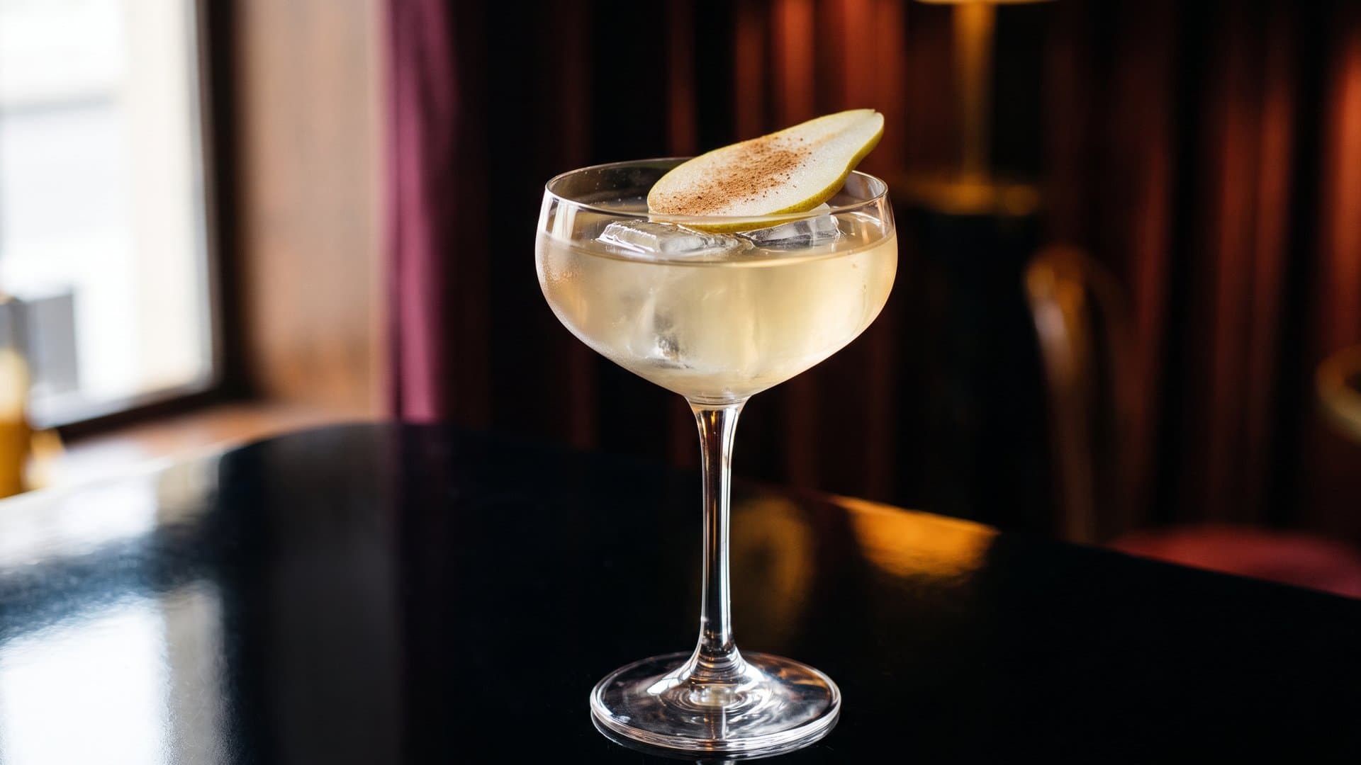 Autumn Orchard cocktail in a coupe garnished with Thin pear slice and light dusting of cinnamon
